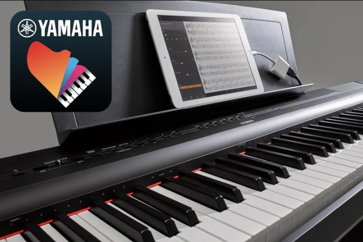 A photo of the Yamaha “Smart Pianist” app icon, together with a tablet displaying a musical score placed on the music stand of the P-125a